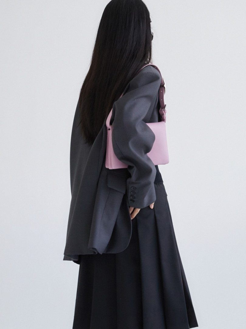 Model wearing a dark oversized outfit with a pink shoulder bag