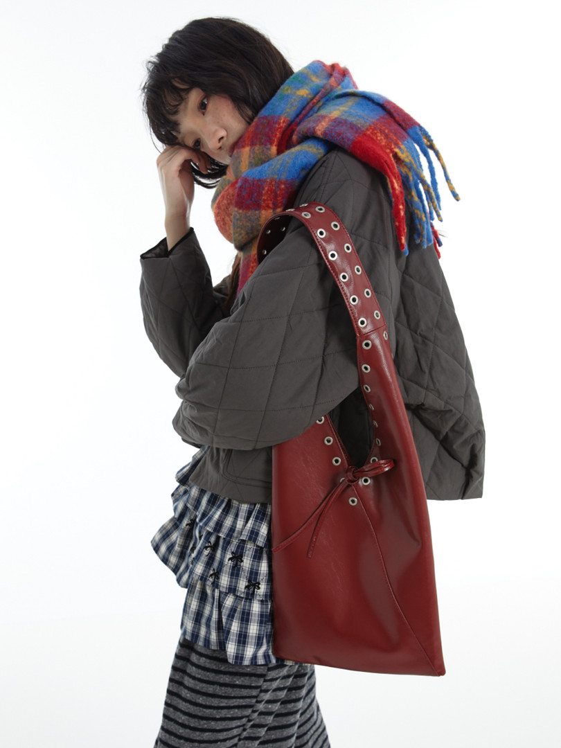 Fashion model wearing a quilted jacket, colorful scarf, and red shoulder bag