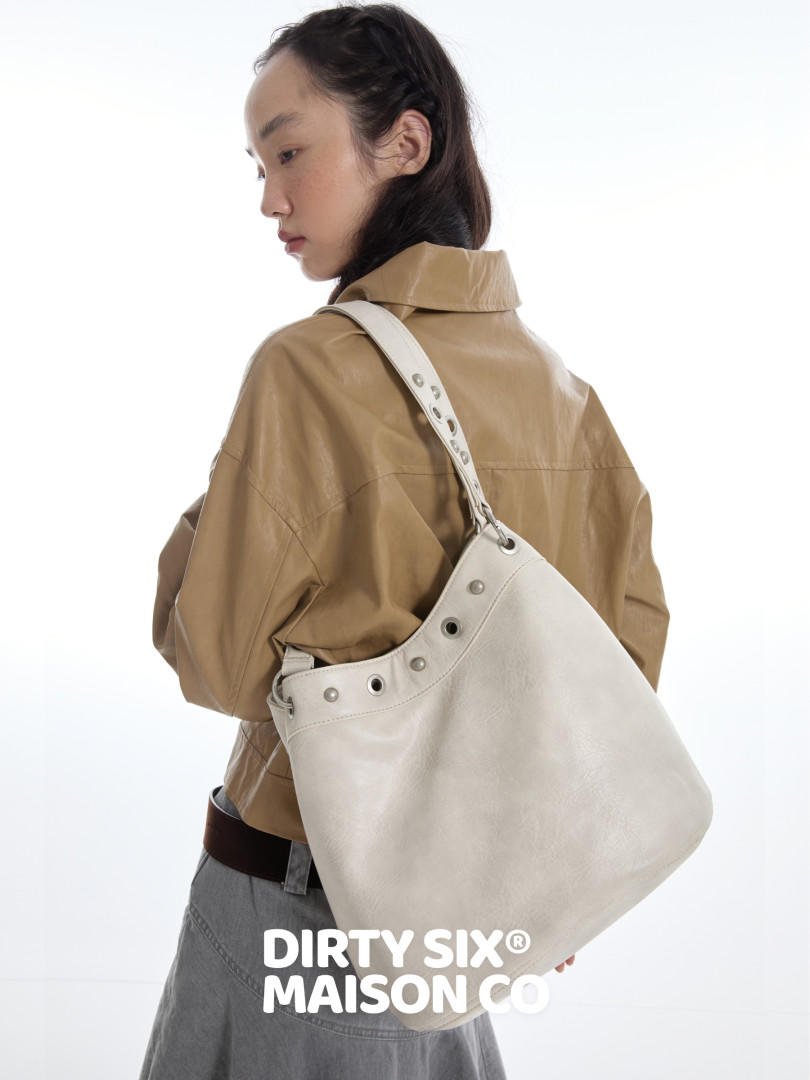 Model wearing a large light beige shoulder tote bag