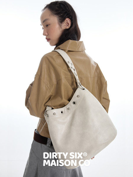 Model wearing a large light beige shoulder tote bag