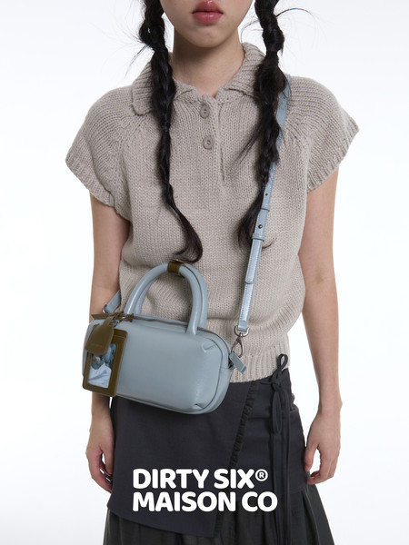 Model wearing a beige sleeveless knit collared top with a light blue crossbody bag