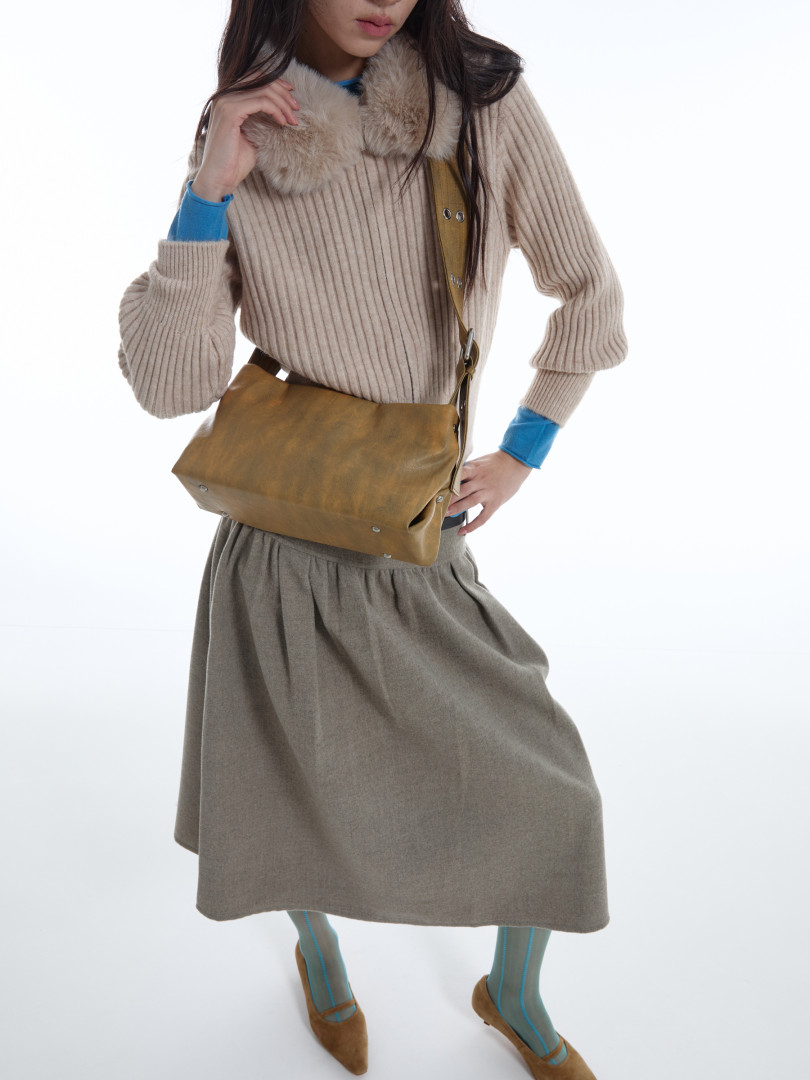 Model wearing a beige ribbed sweater with faux fur collar and a brown crossbody bag.
