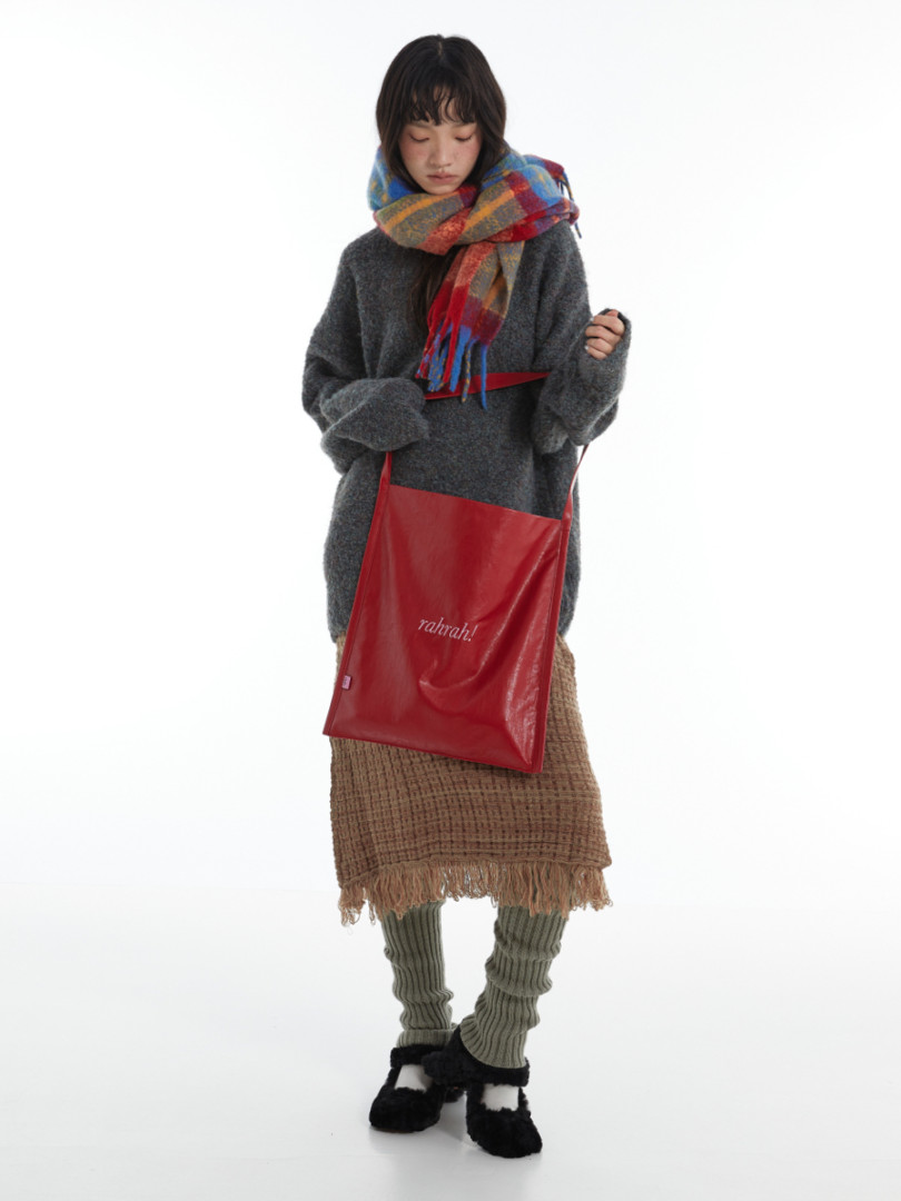 Model wearing a colorful scarf and carrying a red tote bag in a winter outfit