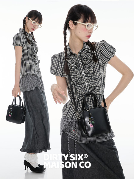 Fashion model wearing a black-and-white checkered blouse with a black handbag