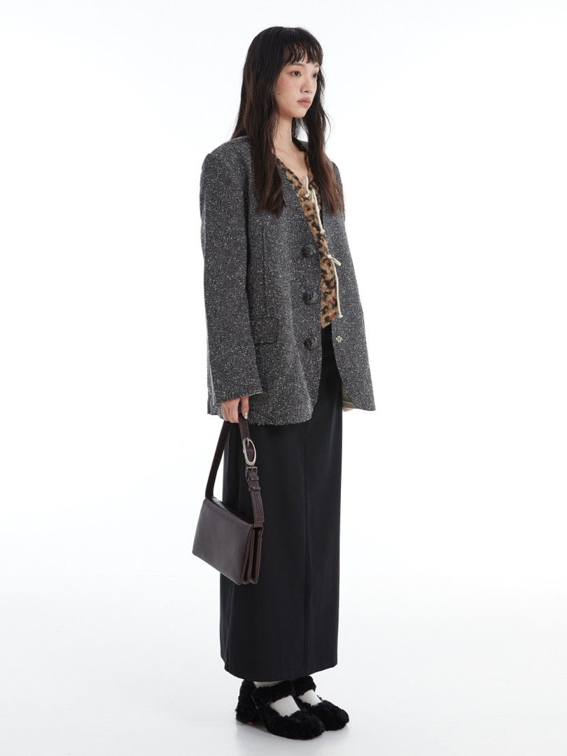 Model wearing a gray textured jacket with a black long skirt and black shoes