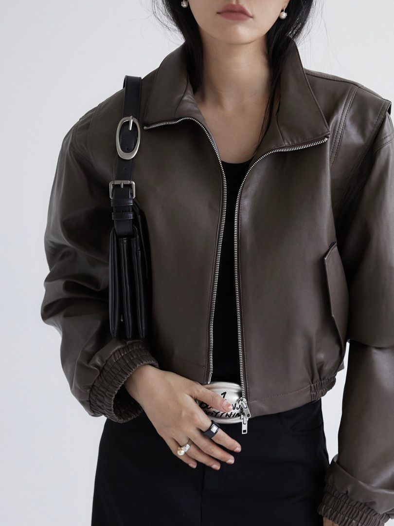 Brown leather jacket worn by a model with a black shoulder bag