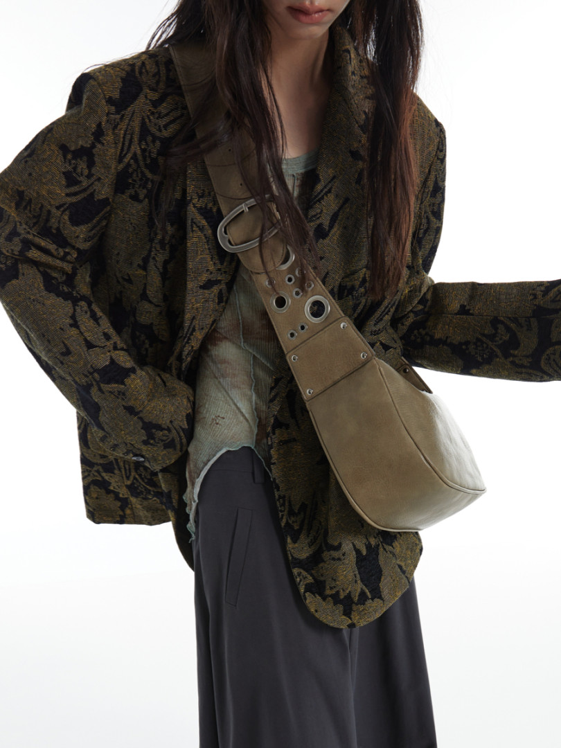 Model wearing a patterned oversized jacket with a tan shoulder bag