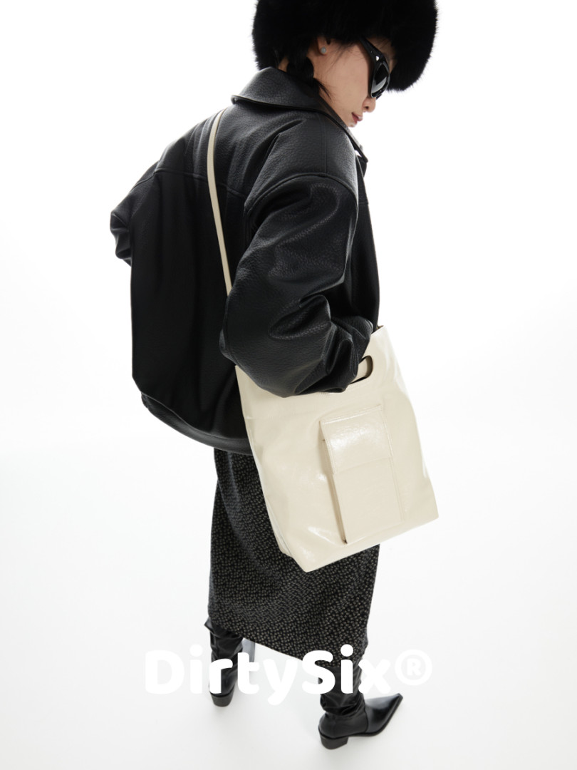 Model wearing a black jacket with a cream shoulder bag