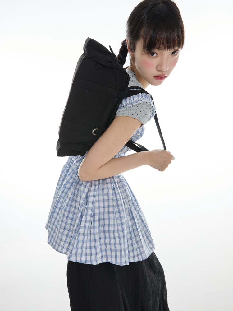 Black backpack worn on a model with a blue plaid dress