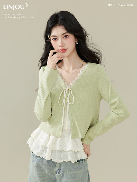 Model wearing a light green cardigan over a lace layered top and jeans
