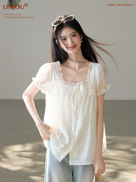 Woman wearing a white lace-trim short-sleeve blouse with buttons and a tie front