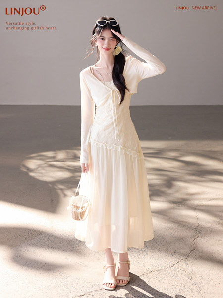 Model wearing a cream long-sleeve maxi dress with lace details and a small woven bag