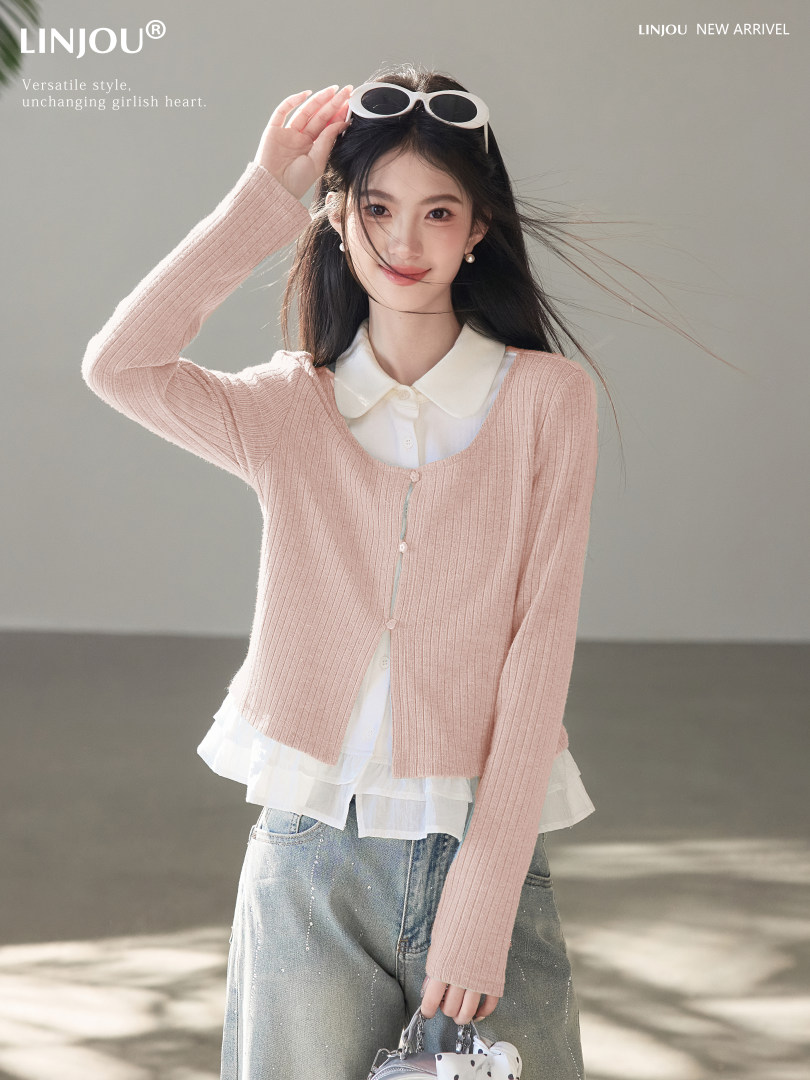 Model wearing a pink ribbed cardigan layered over a white blouse with jeans