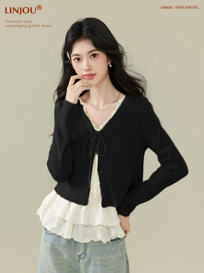 Model wearing a black cropped cardigan over a white lace top with jeans