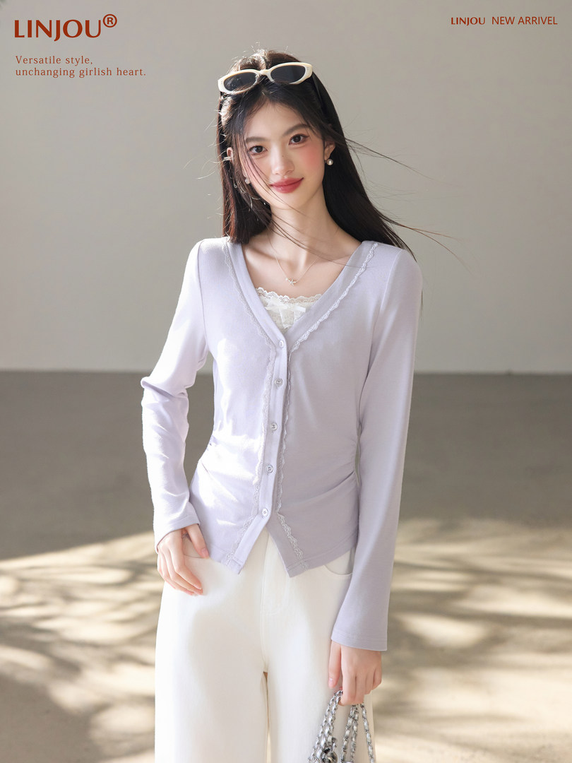 Woman wearing a light lavender button-front cardigan over a white lace top and white pants