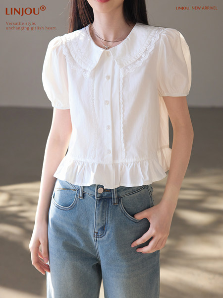 Model wearing a white puff-sleeve blouse with lace trim and blue jeans