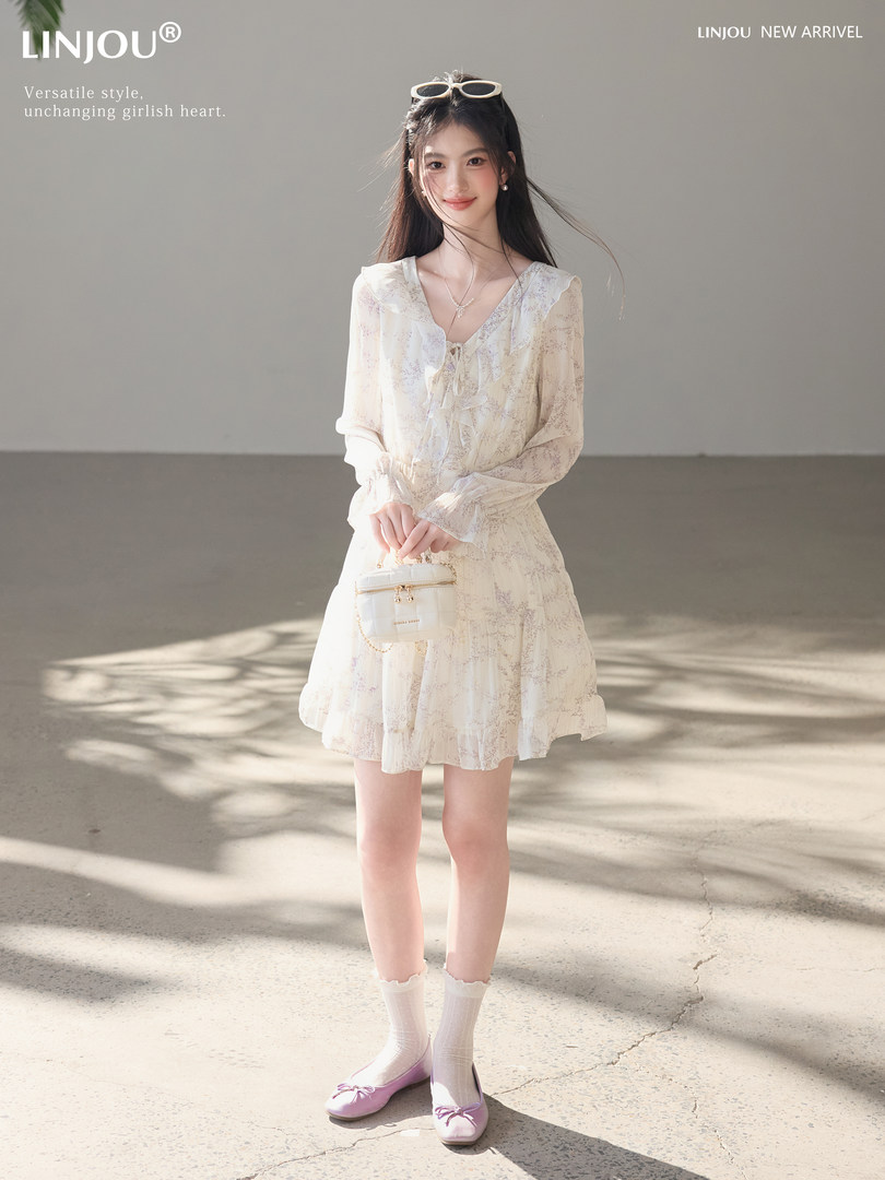 Model wearing a light floral long-sleeve dress with pink flats and a small handbag