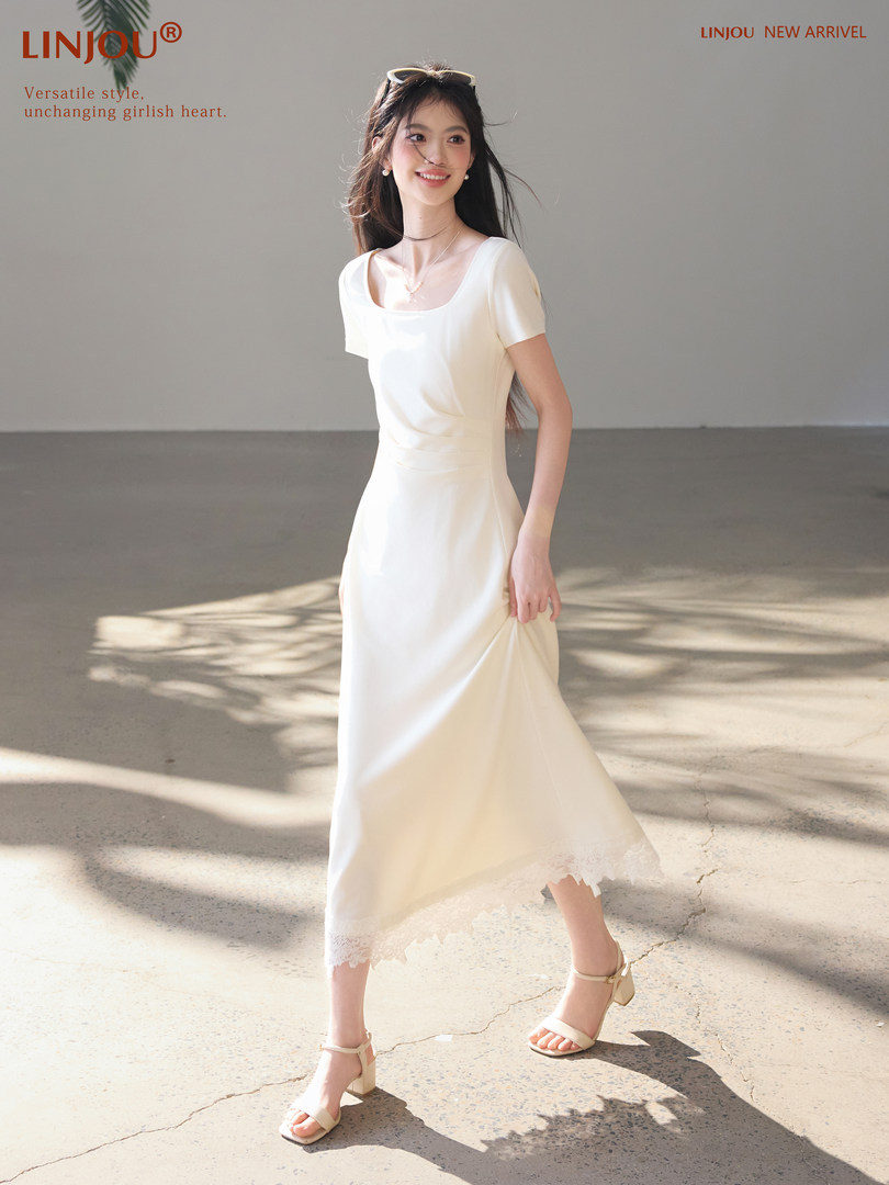 Model wearing a white midi dress with lace hem and heeled sandals