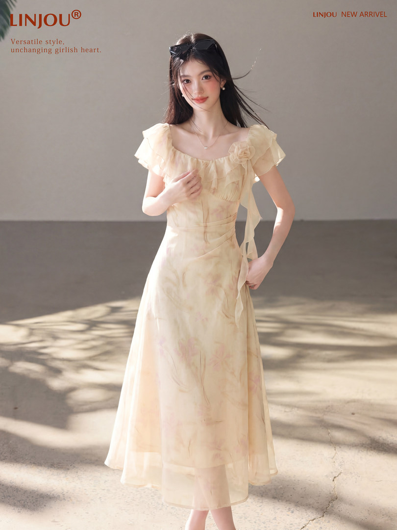 Woman wearing a light cream chiffon dress with flutter sleeves and floral details