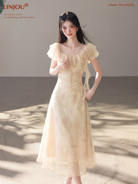 Woman wearing a light cream chiffon dress with flutter sleeves and floral details