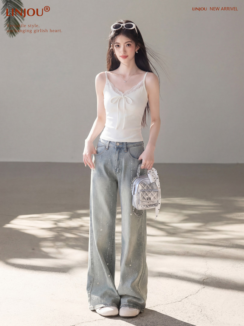 Model wearing a white lace-trim camisole and wide-leg light-wash jeans
