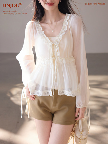 Model wearing a white lace-trim long-sleeve blouse with shorts