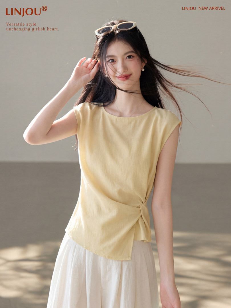 Model wearing a light yellow sleeveless wrap top with a white skirt