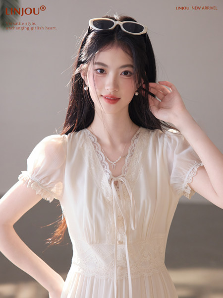 Model wearing a white lace-trimmed short-sleeve dress with a soft, feminine look