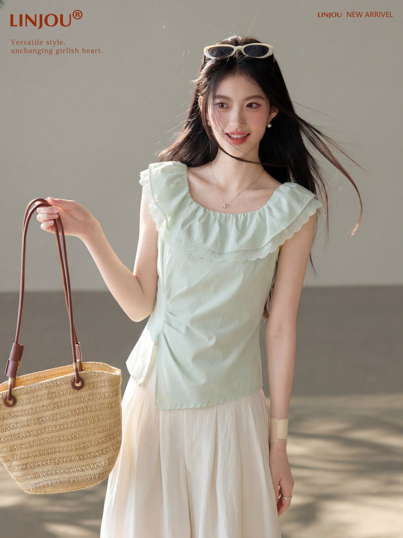 Woman wearing a light mint ruffled sleeveless top with a cream skirt and straw tote bag