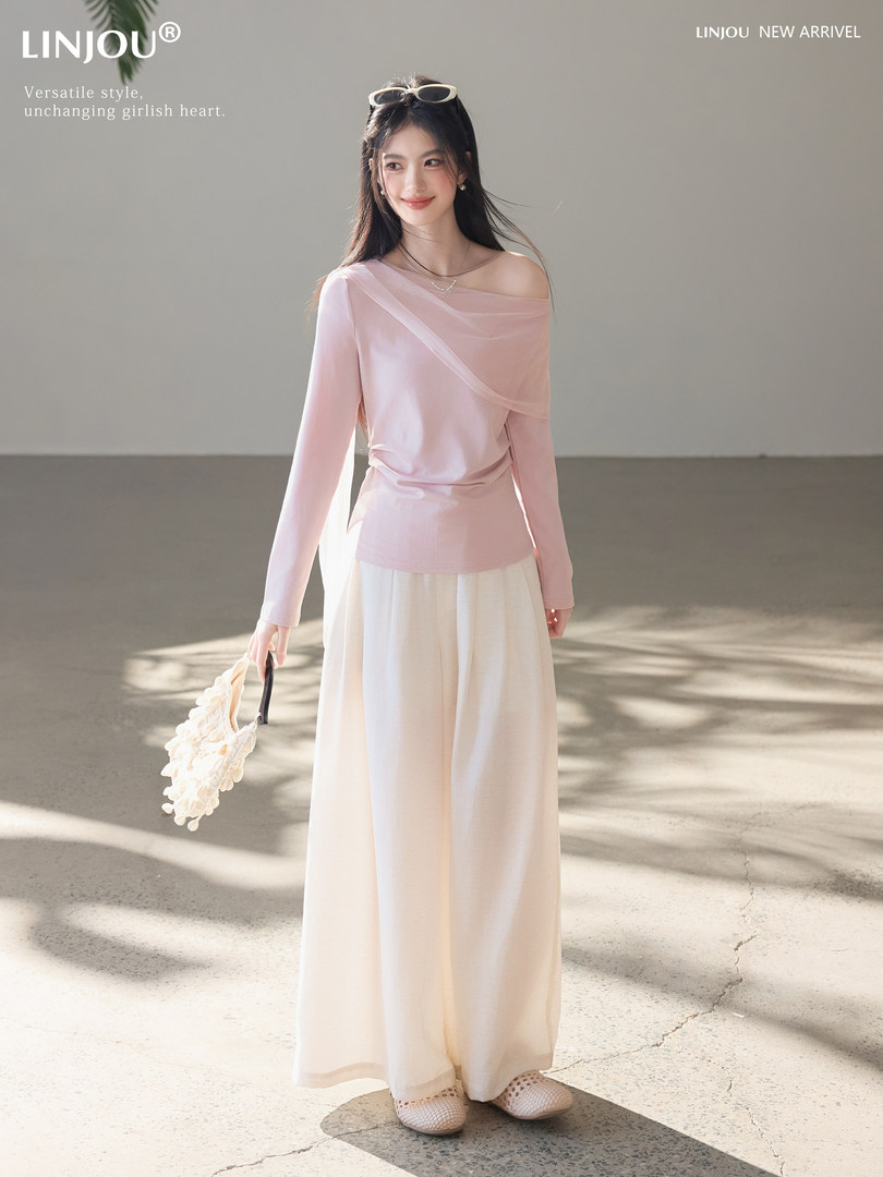 Model wearing a pink off-shoulder long-sleeve top with cream wide-leg pants