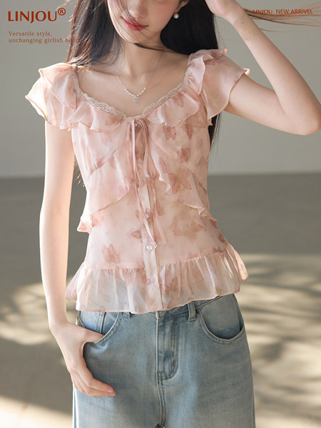 Model wearing a pink ruffled floral blouse with light blue jeans