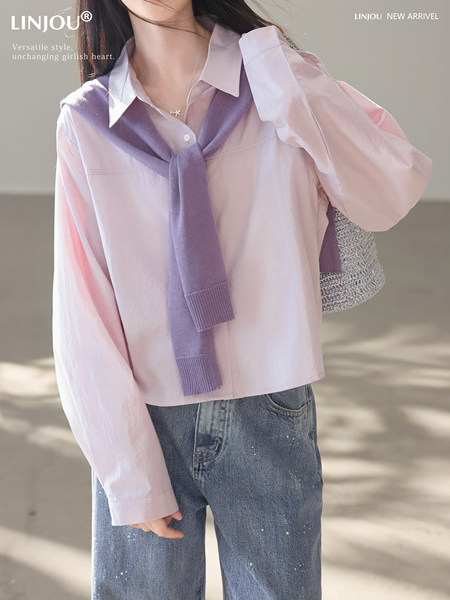 Pastel pink button-up blouse styled with a purple sweater and blue jeans on a model