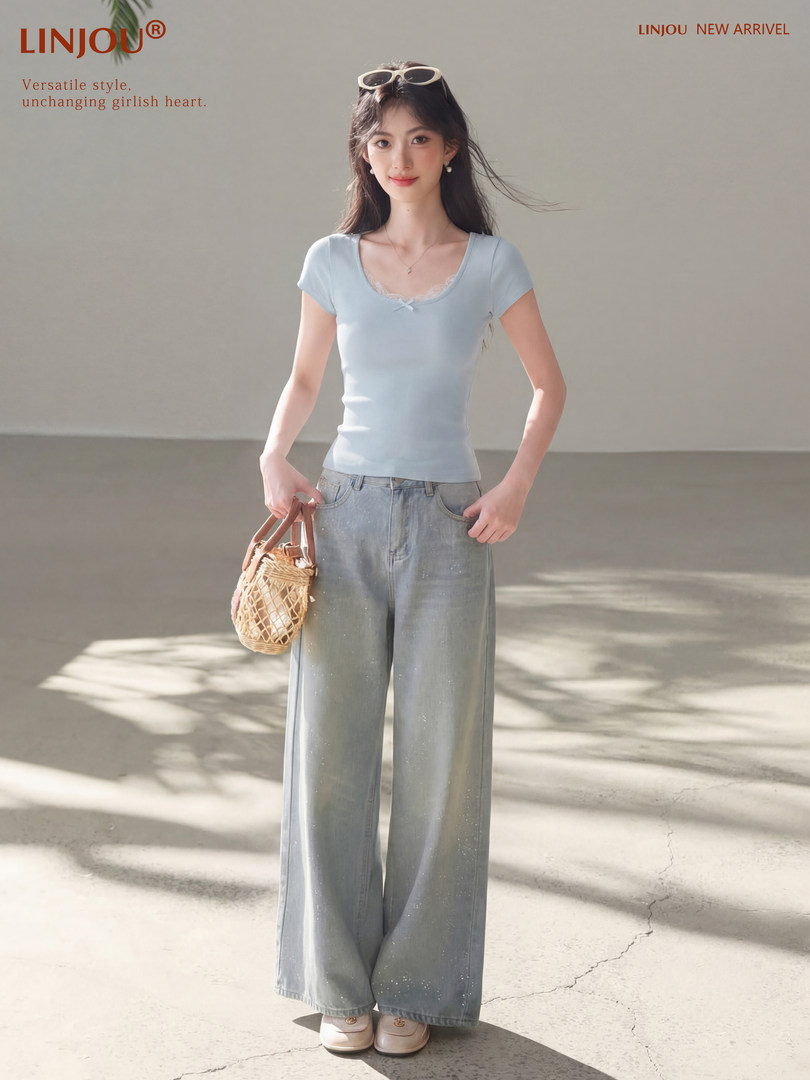 Model wearing a light blue fitted short-sleeve top with wide-leg jeans and a woven handbag