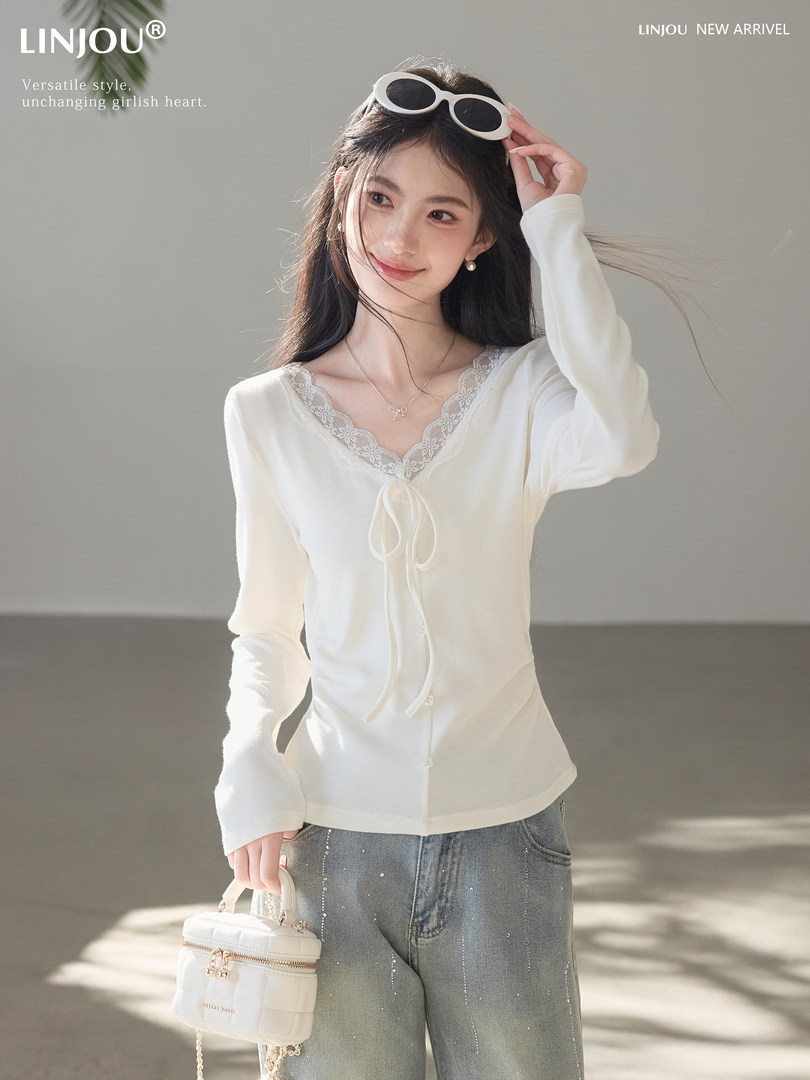 Woman wearing a white lace-trim long-sleeve top with jeans and a small white bag
