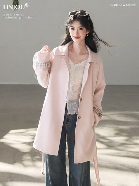 Model wearing a light pink blazer-style coat over a lace top and jeans