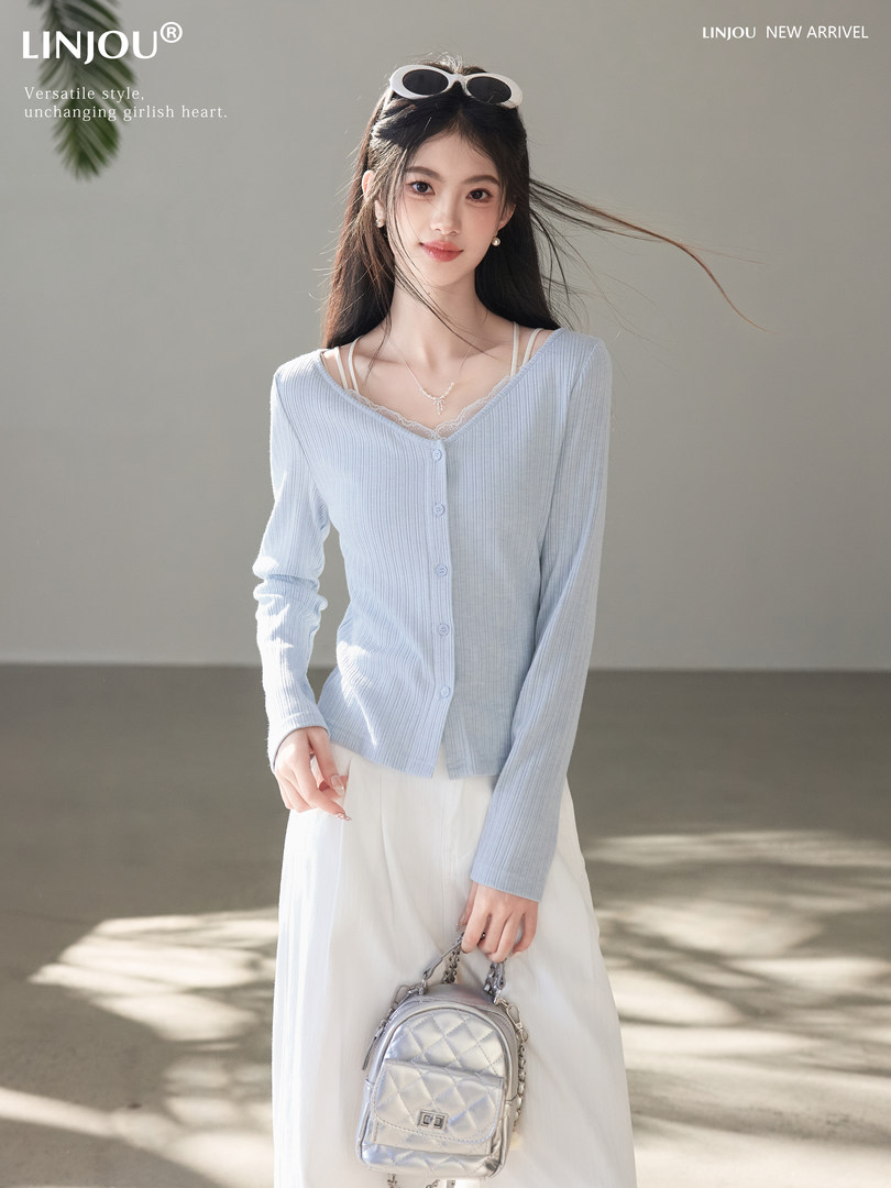 Model wearing a light blue ribbed button-front cardigan with white skirt and small silver handbag