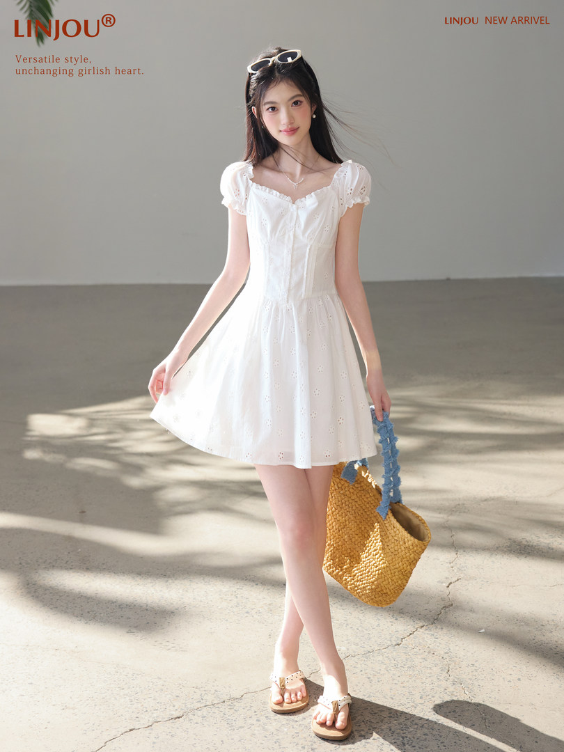 Woman wearing a white short-sleeve mini dress and holding a woven bag