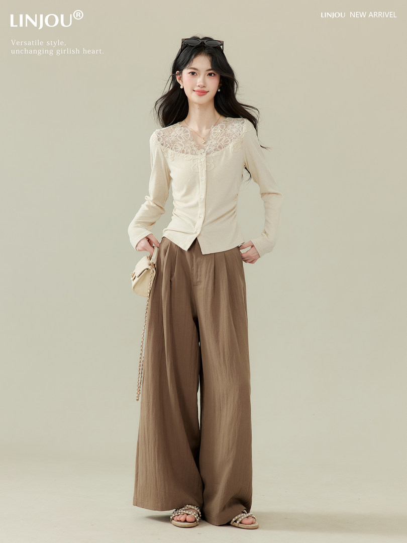 Model wearing a cream lace-trim cardigan with wide-leg brown pants