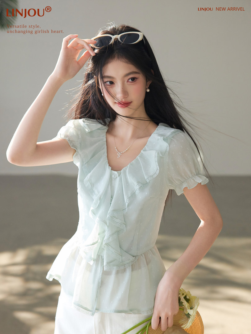 Model wearing a light blue ruffled short-sleeve blouse