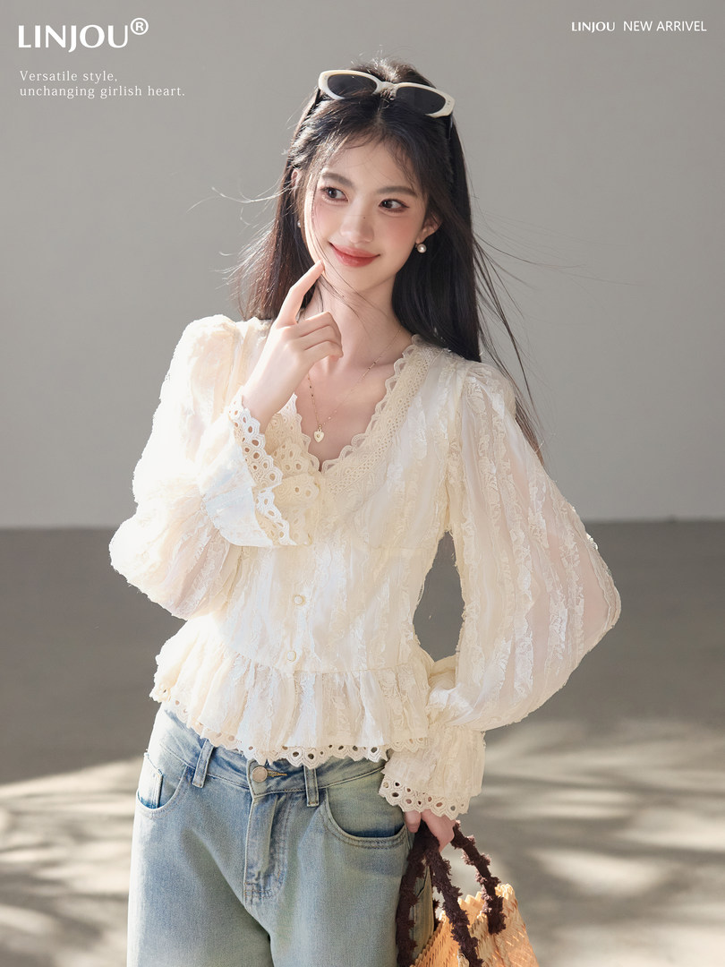 Model wearing a cream lace long-sleeve blouse with light blue jeans