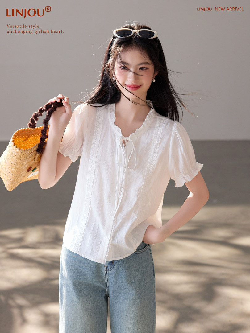 Woman wearing a white short-sleeve blouse with jeans and a woven bag