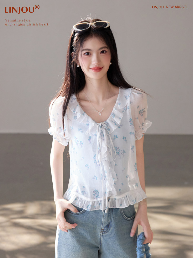 Model wearing a white floral ruffled blouse with blue jeans