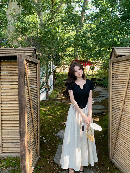 Woman wearing a black-and-white dress outdoors in a garden setting