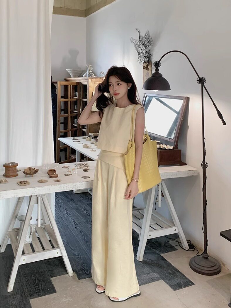 Woman wearing a cream sleeveless top and wide-leg pants with a yellow tote bag