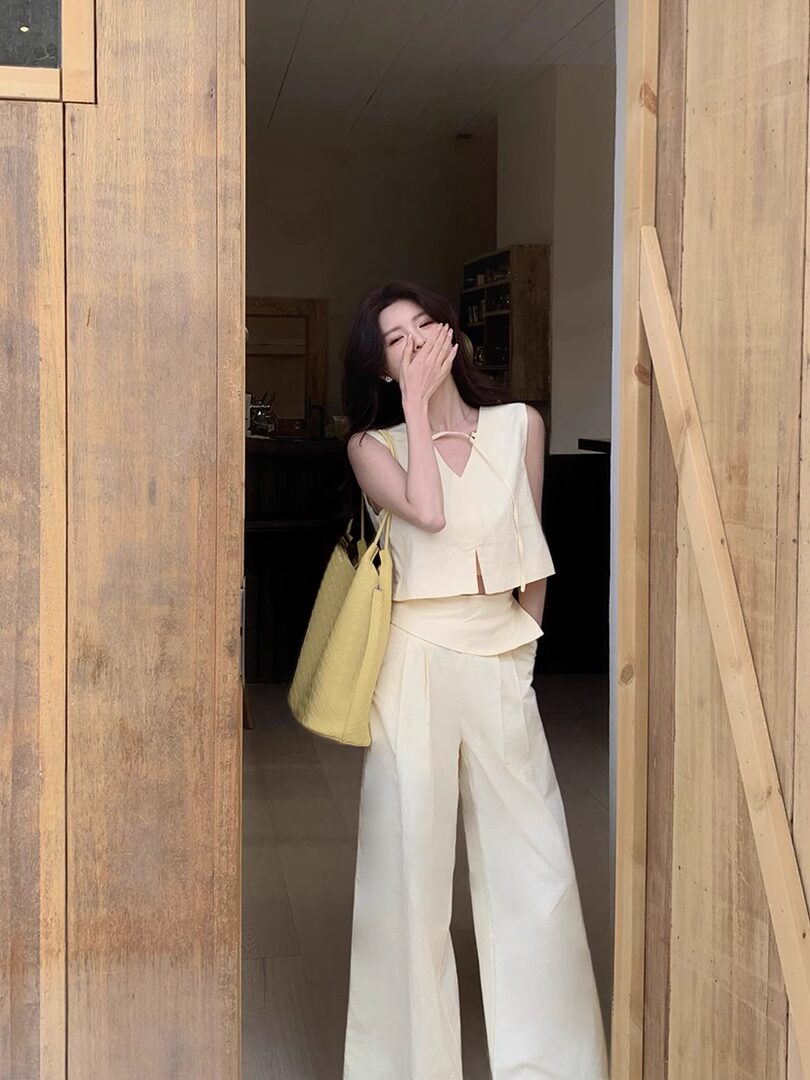 Woman wearing a cream sleeveless top and wide-leg pants with a yellow tote bag