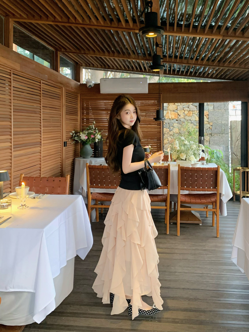 Woman wearing a black top with a beige layered ruffle skirt in a restaurant