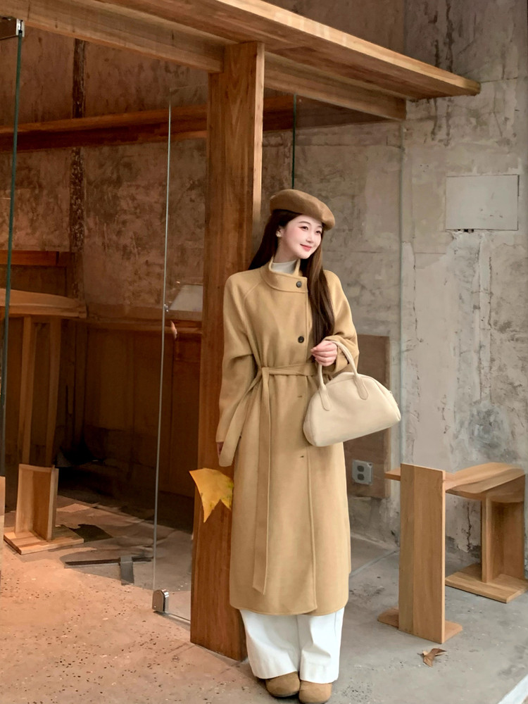 Woman wearing a beige long coat with matching beret and handbag