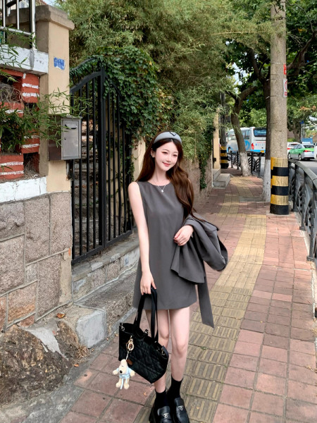 Woman wearing a gray sleeveless dress with a black handbag outdoors