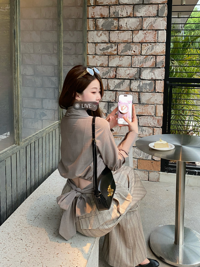 Woman wearing a taupe two-piece outfit with a black crossbody bag at a cafe