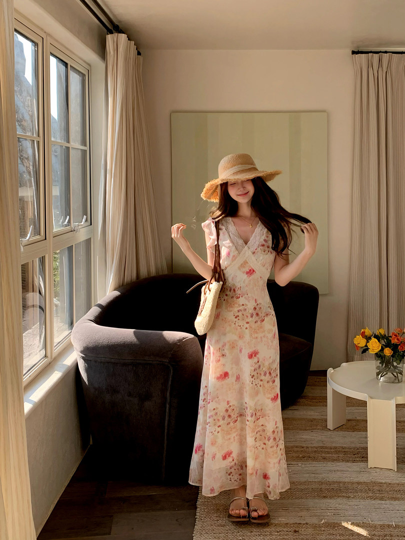 Woman wearing a floral maxi dress with a straw hat and shoulder bag